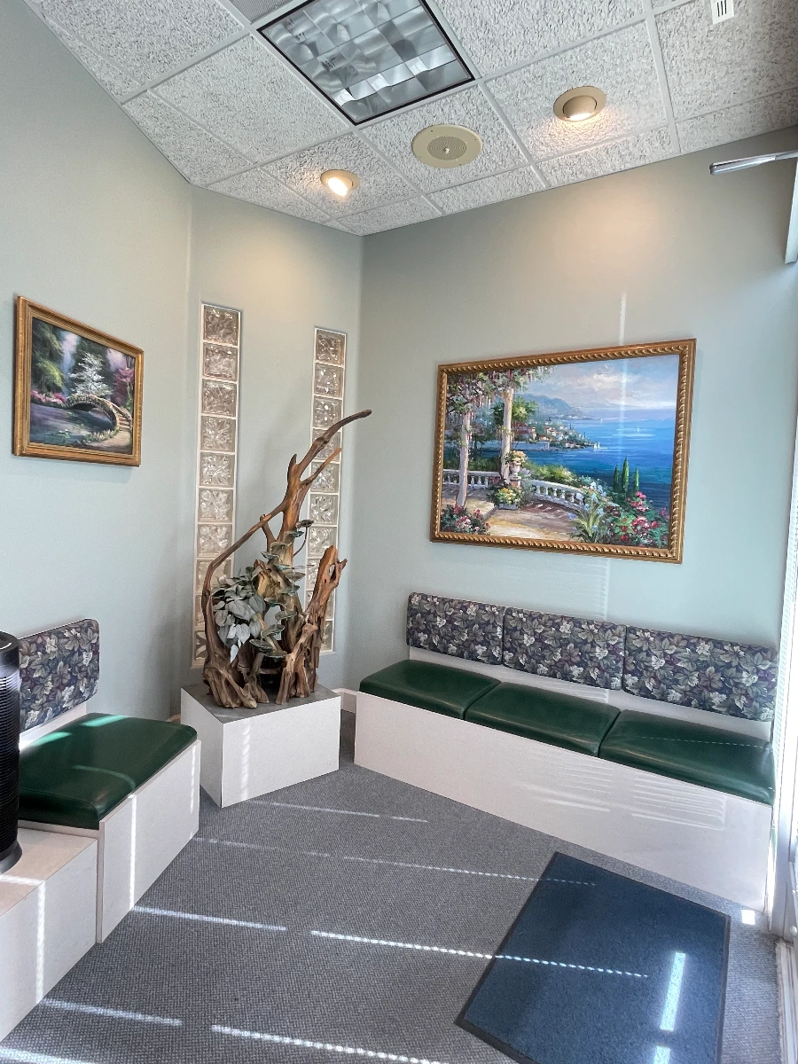 Waiting room with landscape paintings, driftwood decor, and green cushioned seating